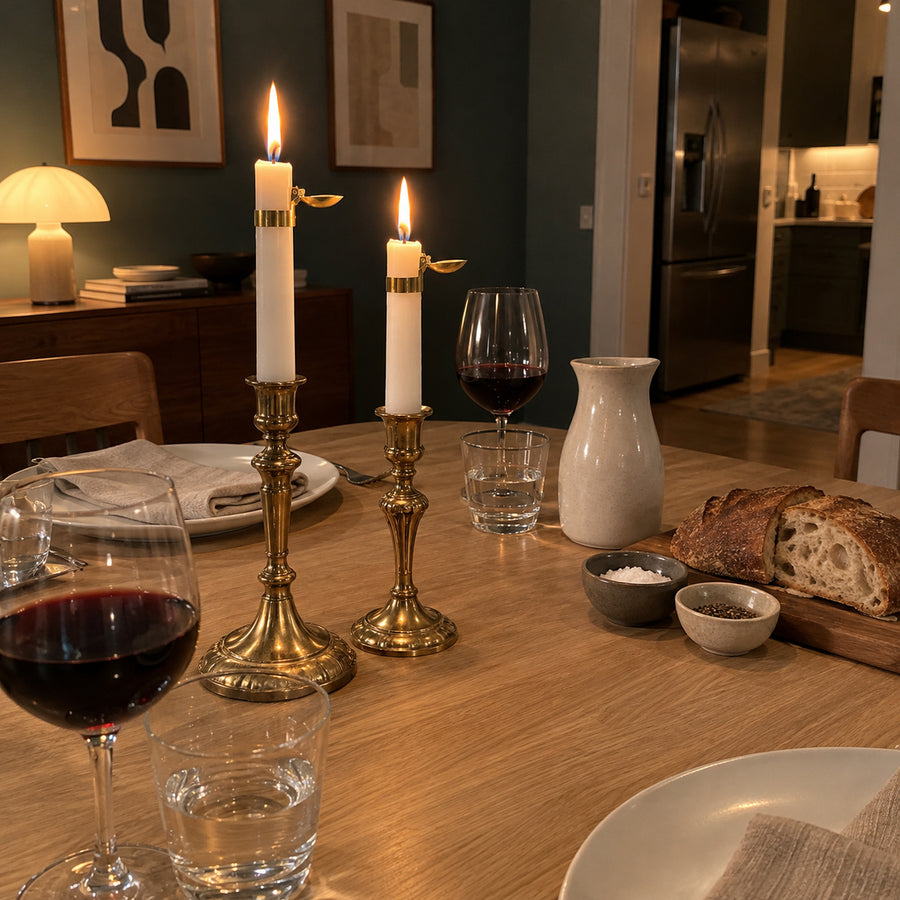 Två kronljus med mässingsfärgade ljussläckare i ljusstakar på ett dukat bord en kväll
