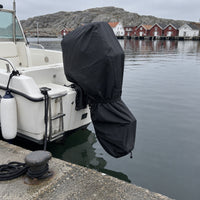 Motorbåt vid en kaj med svart skydd över utombordaren