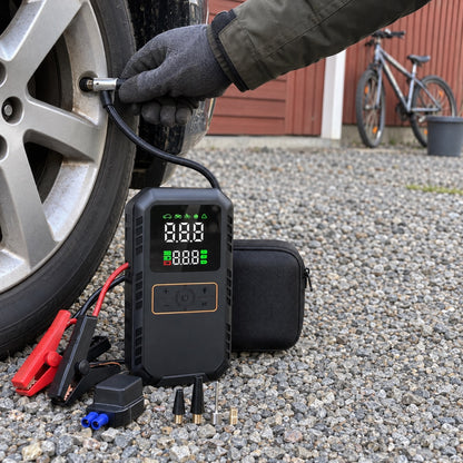 Händer som pumpar bildäck med luftslangen från en svart startbooster