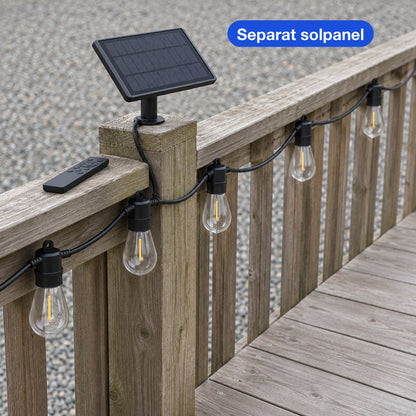 Svart solpanel på en trästolpe med fjärrkontroll och en ljusslinga som hänger längs räcket