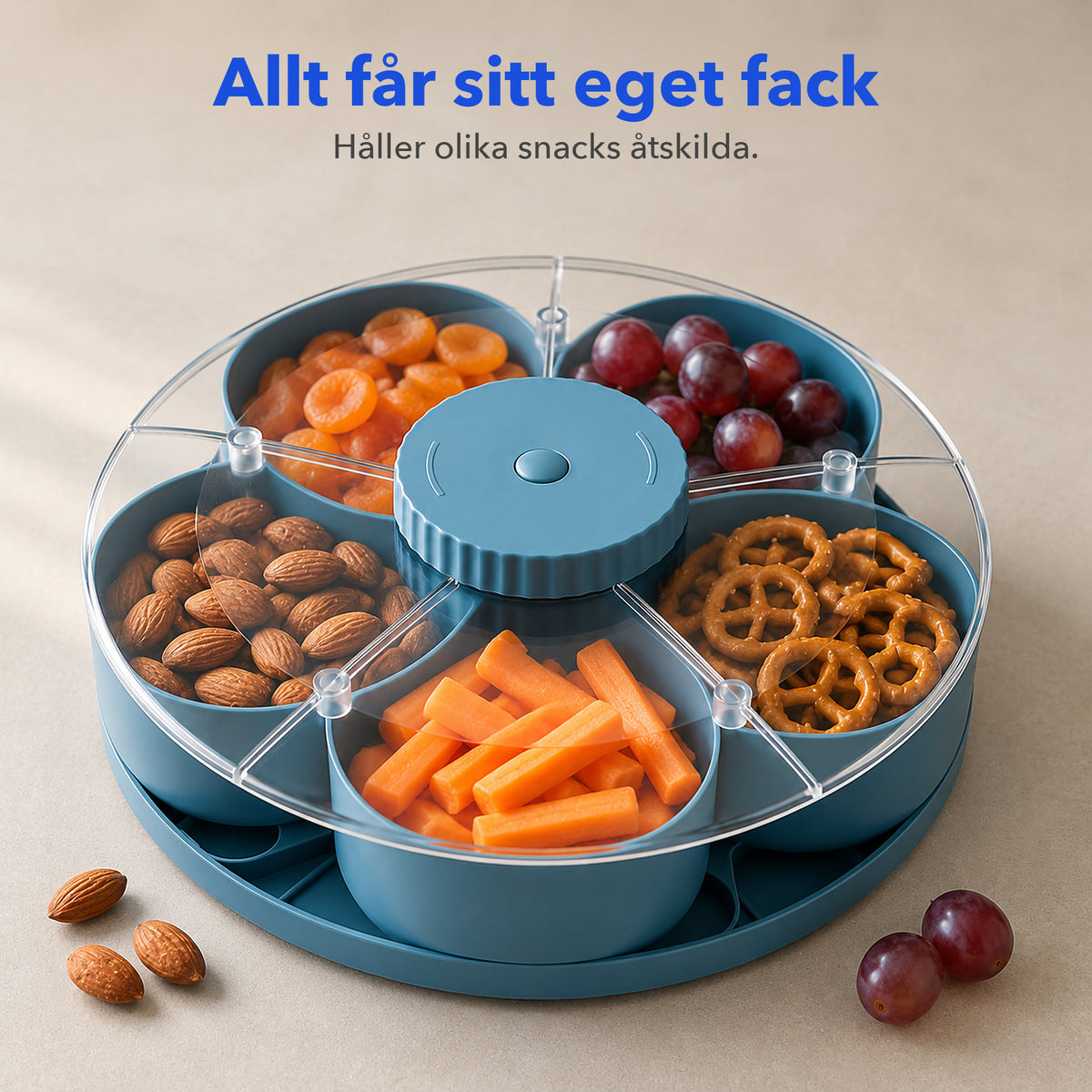 Blå snacksbricka med genomskinligt lock där varje fack håller olika snacks åtskilda: aprikoser, vindruvor, kringlor, morötter och mandel