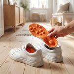 Hand sätter orange ergonomisk innersula i en vit sneaker