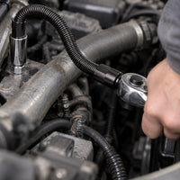 Flexibel hylsförlängare som böjer sig runt ett rör i ett motorrum och når en bult bakom röret