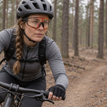 Kvinna cyklar på skogsstig med fotokroma cykelglasögon med klara linser