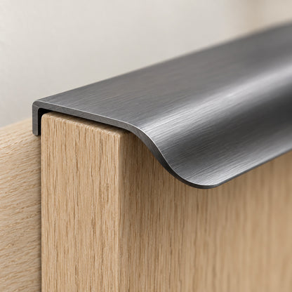 Närbild på änden av ett grått kantgrepp i borstad aluminium på överkanten av en ekdörr