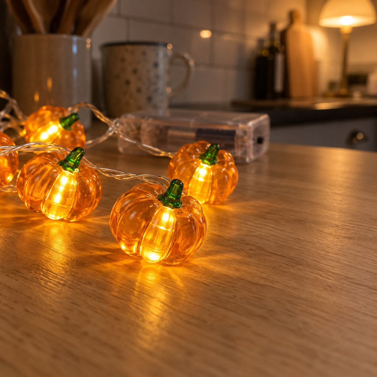 Närbild på ribbade pumpor i bärnstensfärgad akryl med grön stjälk och varmt sken