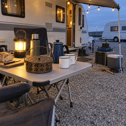Brun myggspiralhållare på ett hopfällbart campingbord framför en husvagn på en campingplats