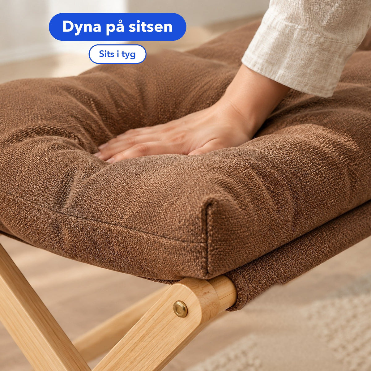 En hand ligger på den bruna dynan på den vikbara pallen i trä, med texterna Dyna på sitsen och Sits i tyg