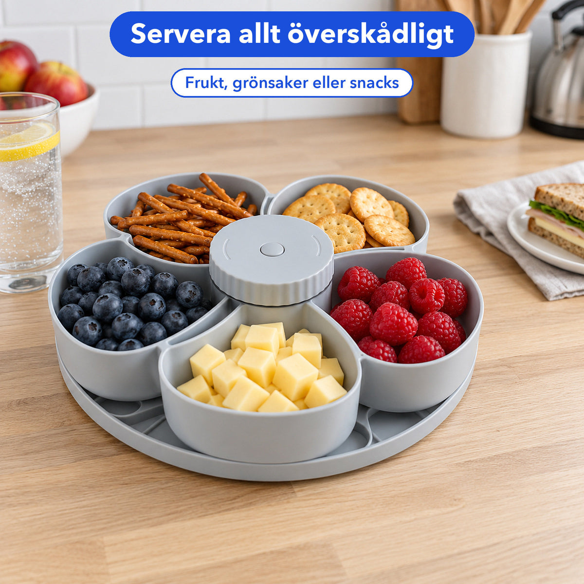 Grå snacksbricka med kringlor, kex, hallon, blåbär och ostkuber på en köksbänk