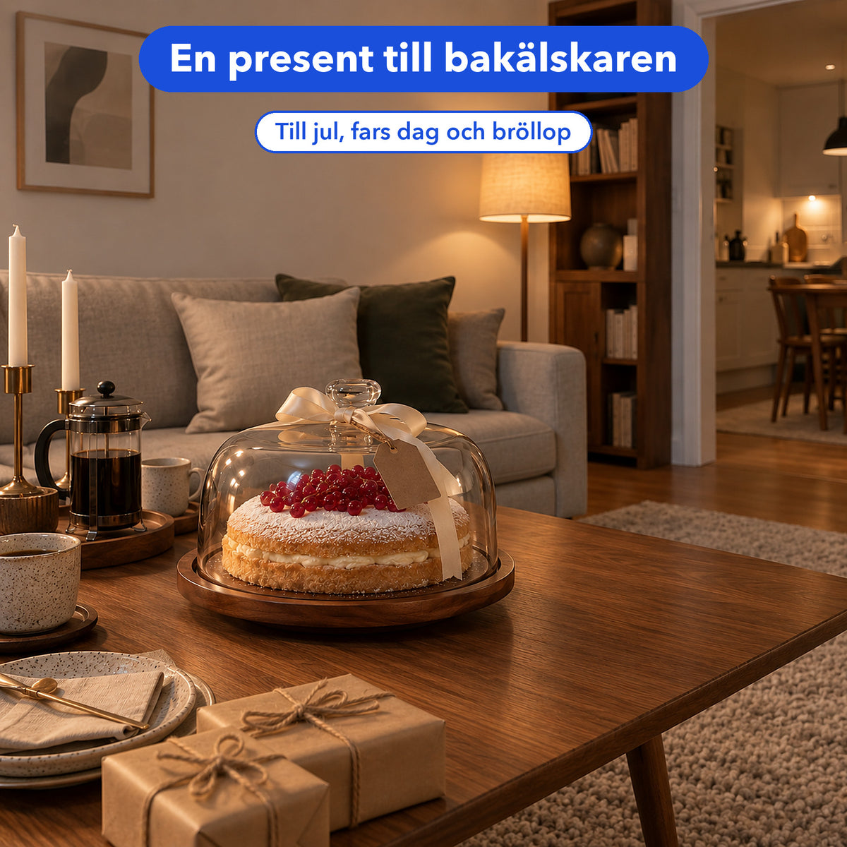 Tårta under kupol på träbricka med sidenband och presentpaket på ett soffbord i ett inrett vardagsrum