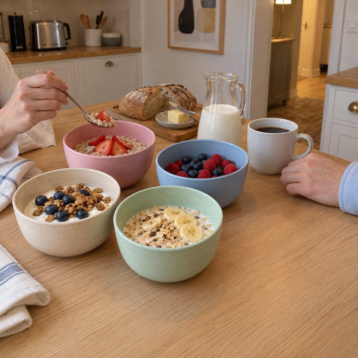 Fyra pastellfärgade skålar fyllda med yoghurt, gröt, müsli och bär på ett frukostbord i ett svenskt kök