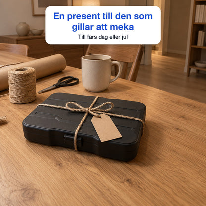 Skruvmejselsetets fodral insvept som present med jutesnöre och en tom etikett, bredvid kraftpapper, sax och en mugg, till fars dag eller jul